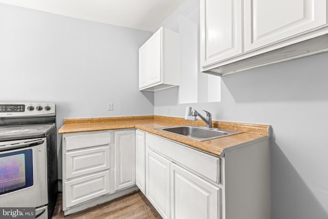 kitchen featuring white cabinets, stainless steel electric stove, a sink, wood finished floors, and light countertops