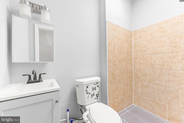 full bath featuring a tile shower, toilet, and vanity