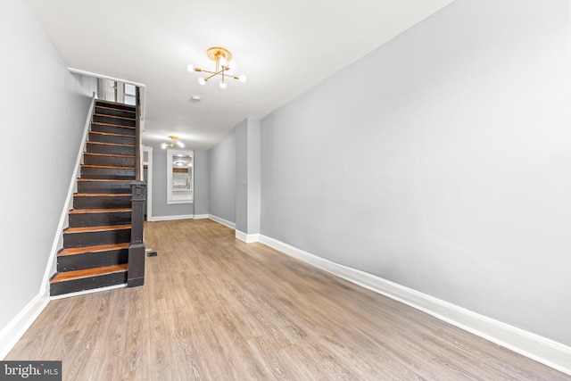staircase with baseboards, wood finished floors, and an inviting chandelier