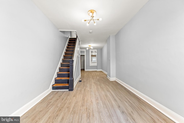 interior space featuring wood finished floors, baseboards, and a notable chandelier