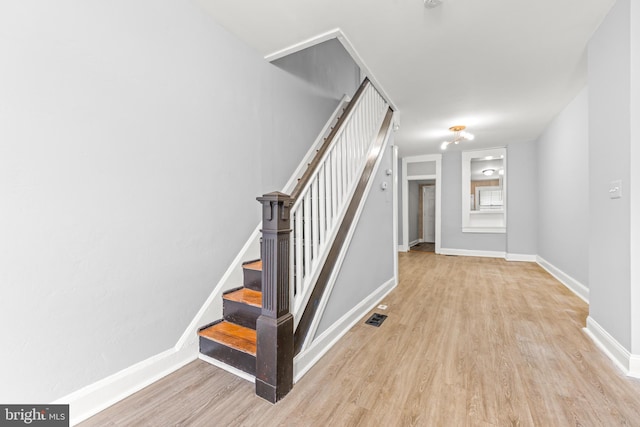 stairway featuring baseboards, wood finished floors, and visible vents