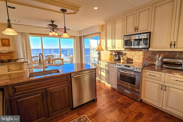 kitchen with ceiling fan, decorative backsplash, a sink, appliances with stainless steel finishes, and cream cabinets