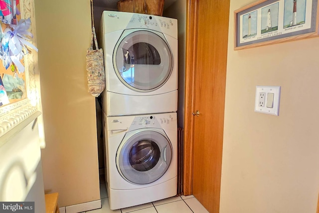 laundry area featuring light tile patterned floors, stacked washer and dryer, and laundry area