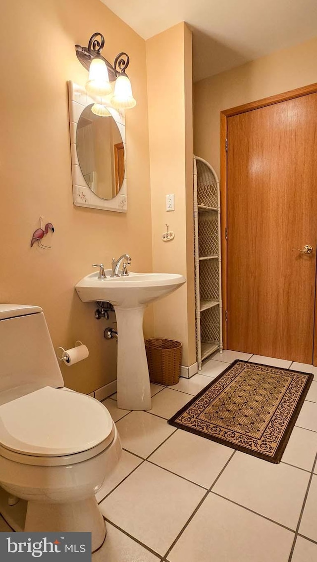 bathroom featuring tile patterned floors, toilet, and a sink