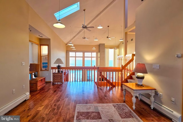 interior space with a baseboard heating unit, a skylight, wood finished floors, and high vaulted ceiling