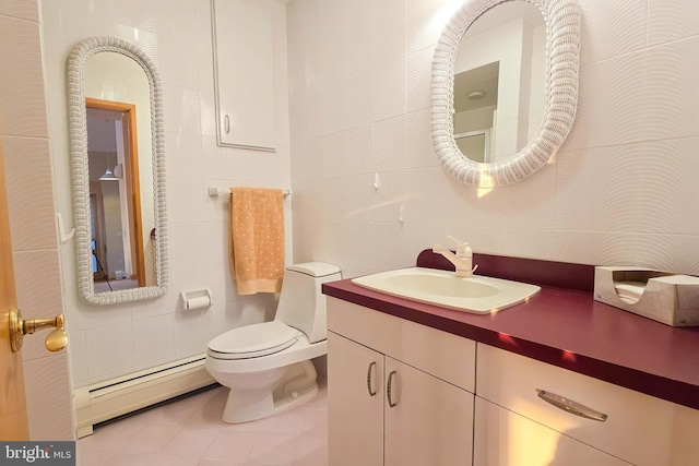 bathroom with tile patterned flooring, toilet, vanity, baseboard heating, and tile walls