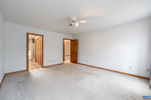 unfurnished bedroom featuring arched walkways, baseboards, ensuite bathroom, and light carpet