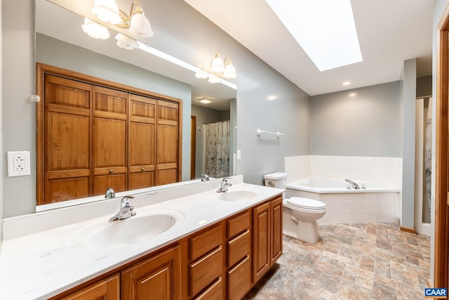 full bath with double vanity, a skylight, a sink, stone finish flooring, and a bath