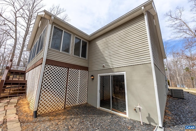 back of house featuring stairs, central AC, and stucco siding