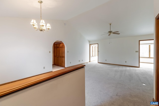 unfurnished room with baseboards, light colored carpet, ceiling fan with notable chandelier, arched walkways, and high vaulted ceiling