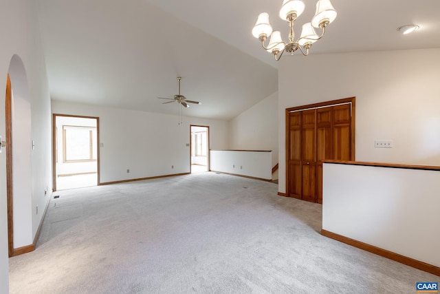 empty room with baseboards, arched walkways, vaulted ceiling, light carpet, and ceiling fan with notable chandelier