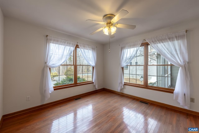 spare room with visible vents, baseboards, and wood-type flooring