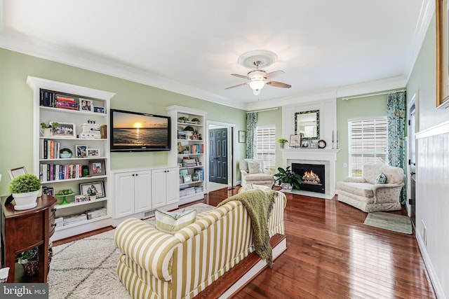 living room with crown molding, a fireplace with flush hearth, wood-type flooring, and a wealth of natural light