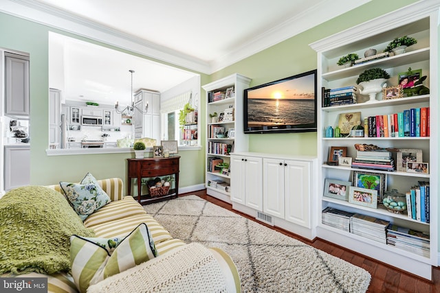 living room with a chandelier, visible vents, wood finished floors, and ornamental molding