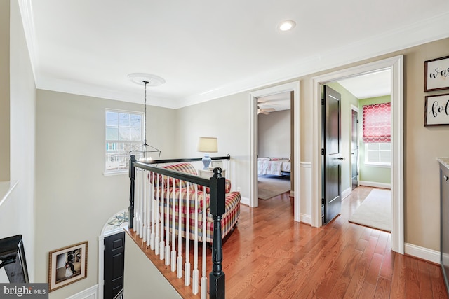 hall featuring an upstairs landing, crown molding, baseboards, and wood finished floors