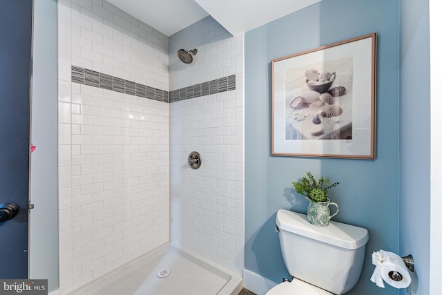 full bath featuring tiled shower and toilet