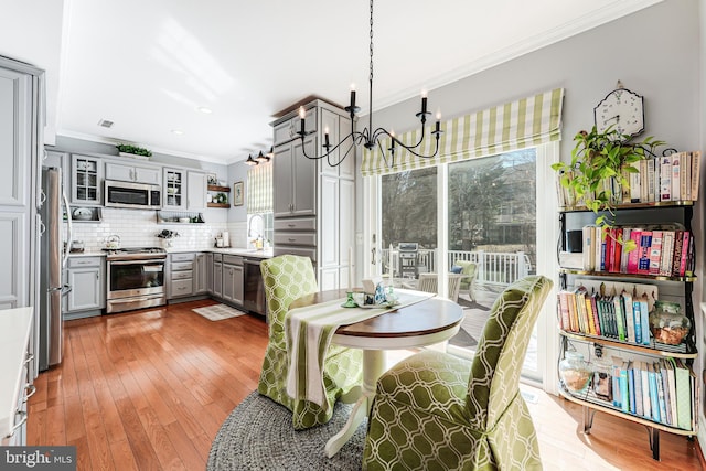 dining space with an inviting chandelier, crown molding, visible vents, and light wood-type flooring