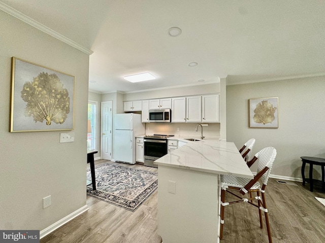 kitchen with crown molding, light stone countertops, a peninsula, stainless steel appliances, and a sink