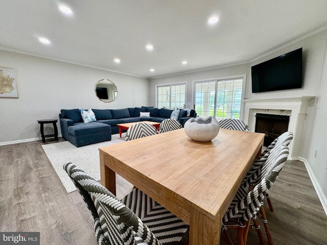 dining area with wood finished floors, baseboards, recessed lighting, a high end fireplace, and ornamental molding