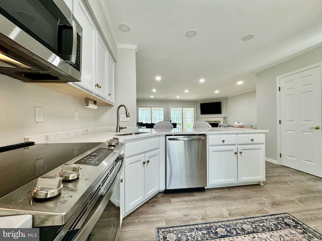 kitchen featuring white cabinetry, a peninsula, appliances with stainless steel finishes, and a sink