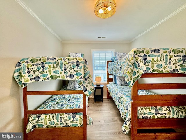 bedroom featuring visible vents, wood finished floors, and ornamental molding