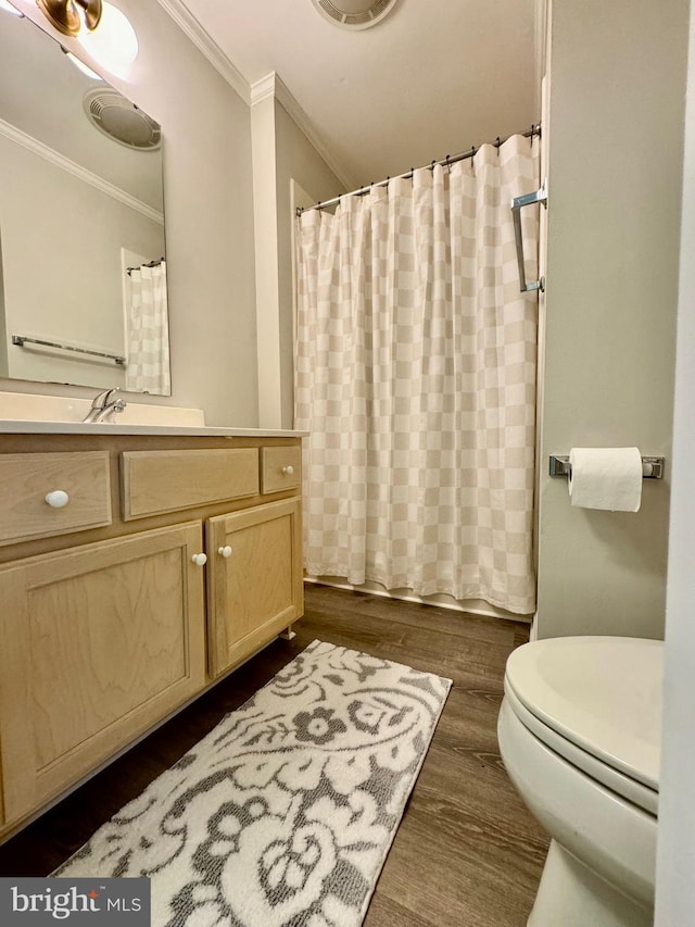 bathroom with wood finished floors, toilet, vanity, and ornamental molding