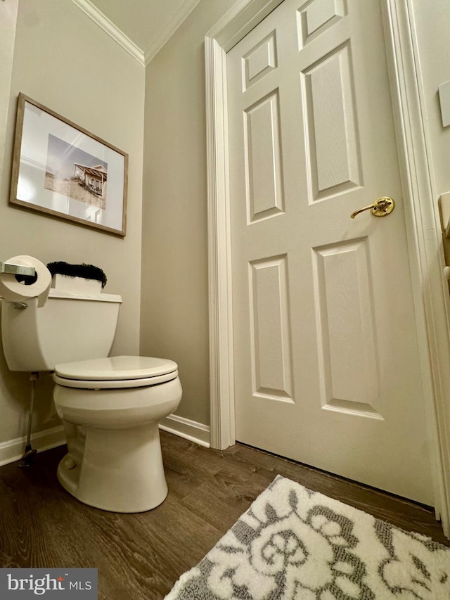 bathroom featuring baseboards, wood finished floors, toilet, and ornamental molding