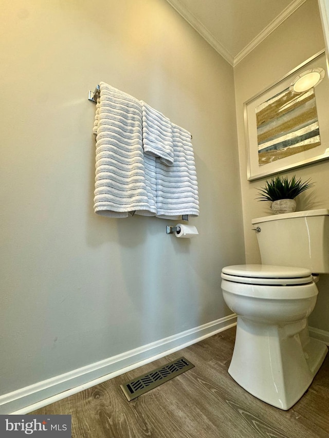 bathroom featuring visible vents, baseboards, toilet, ornamental molding, and wood finished floors