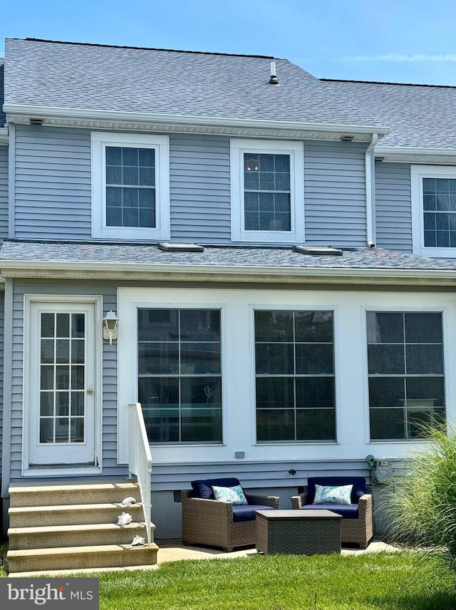 rear view of house featuring entry steps, an outdoor hangout area, and a shingled roof