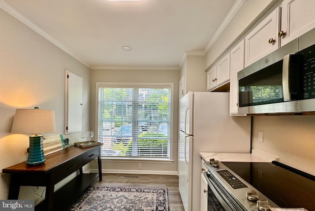 kitchen with baseboards, stainless steel appliances, light wood-style floors, white cabinetry, and crown molding