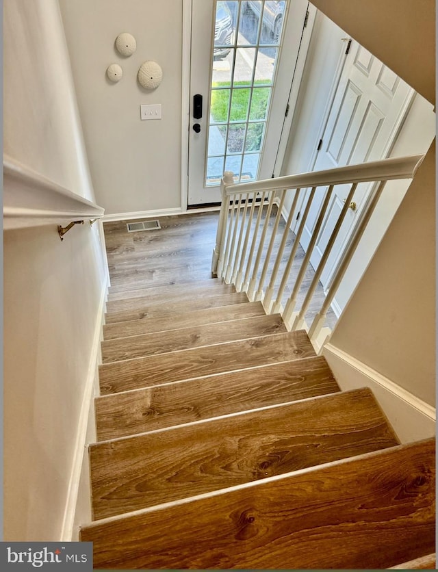 stairs with visible vents, baseboards, and wood finished floors