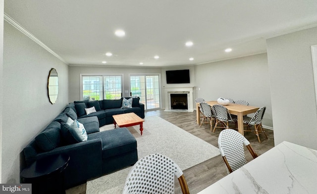 living area featuring recessed lighting, wood finished floors, a high end fireplace, and ornamental molding