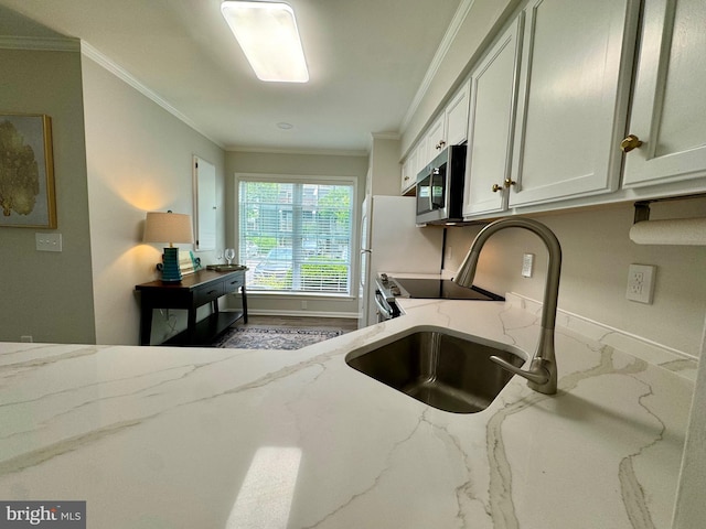 kitchen with light stone counters, stainless steel microwave, white cabinetry, and ornamental molding