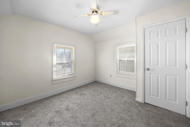 carpeted empty room featuring a healthy amount of sunlight, baseboards, lofted ceiling, and ceiling fan