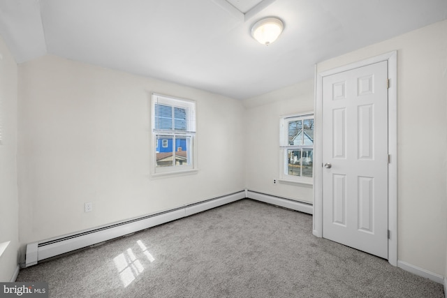 carpeted empty room with a baseboard heating unit and lofted ceiling