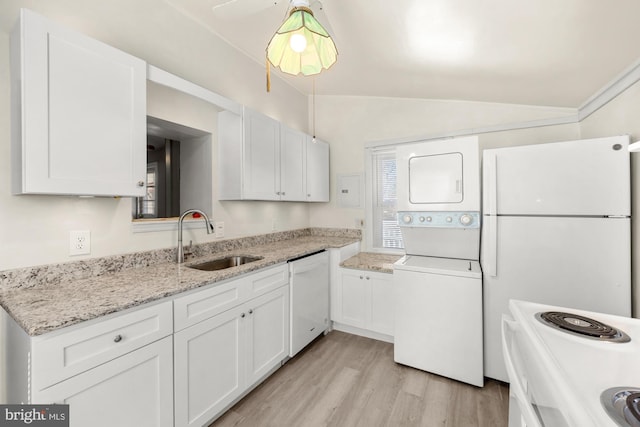 kitchen with stacked washer / dryer, vaulted ceiling, white appliances, white cabinetry, and a sink