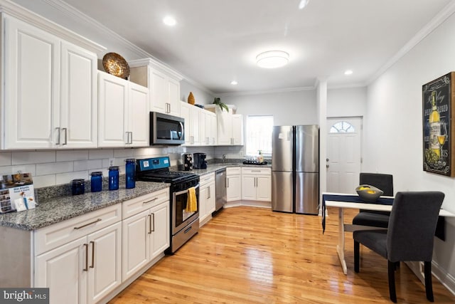 kitchen featuring ornamental molding, backsplash, stainless steel appliances, white cabinets, and light wood finished floors