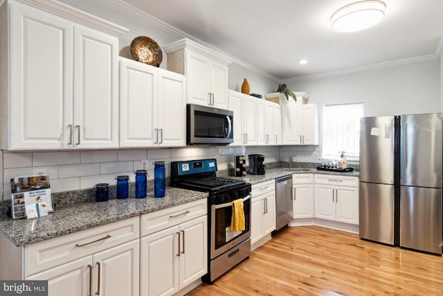 kitchen with backsplash, crown molding, light wood-style floors, white cabinets, and stainless steel appliances