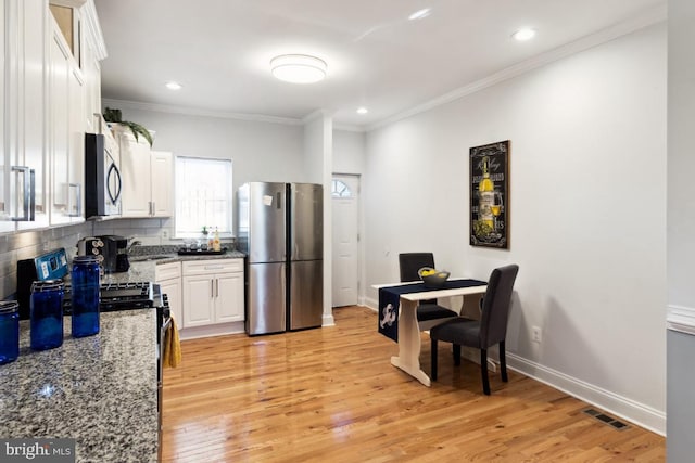 kitchen with light wood-style flooring, white cabinetry, stainless steel appliances, and ornamental molding