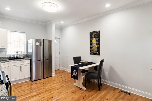 dining room featuring baseboards, light wood-style floors, visible vents, and ornamental molding