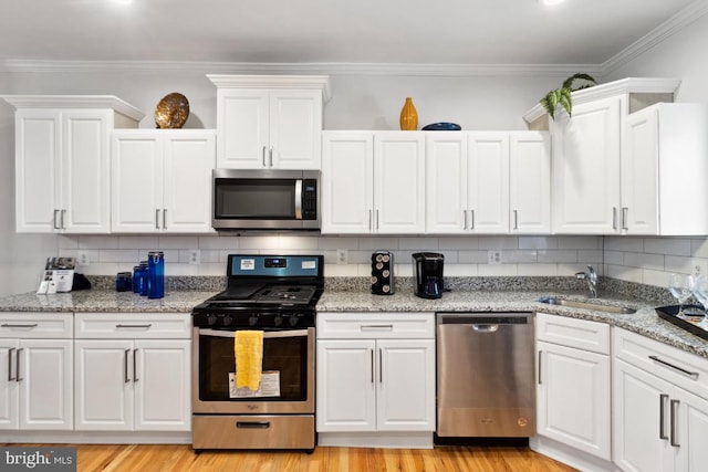 kitchen with tasteful backsplash, light wood-style flooring, appliances with stainless steel finishes, white cabinetry, and a sink