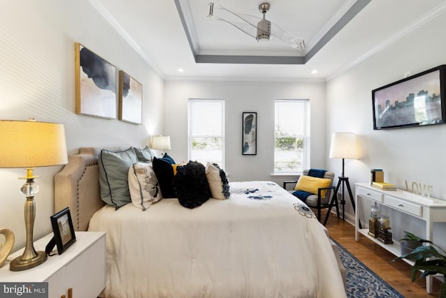 bedroom featuring recessed lighting, wood finished floors, a tray ceiling, and ornamental molding