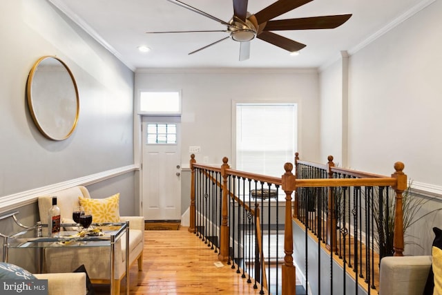 staircase featuring wood finished floors, a ceiling fan, and ornamental molding