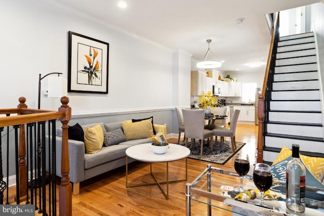 living area with light wood-type flooring, recessed lighting, stairway, crown molding, and baseboards