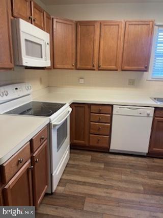 kitchen featuring white appliances, brown cabinets, dark wood-style floors, and light countertops