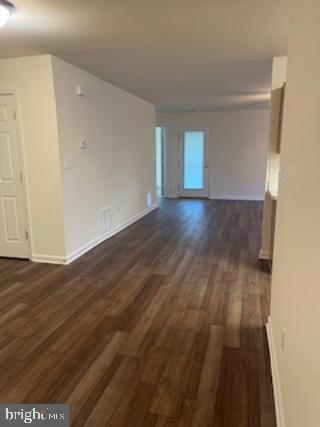 empty room with baseboards and dark wood-style flooring