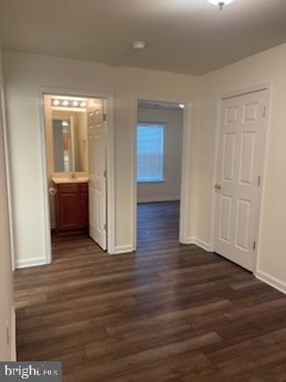 hall featuring dark wood-style floors and baseboards