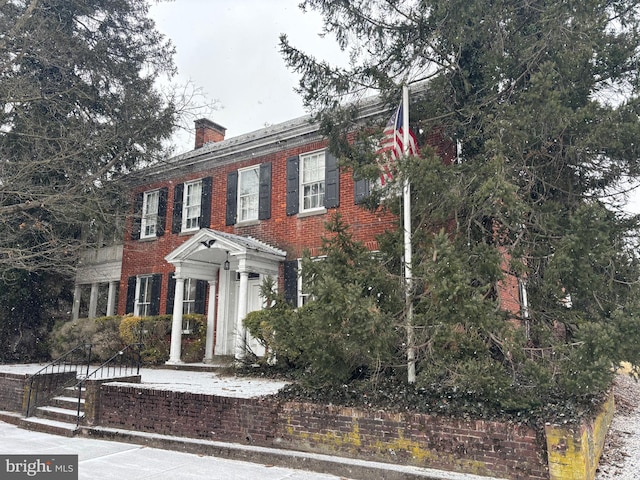 view of front of home with brick siding and a chimney