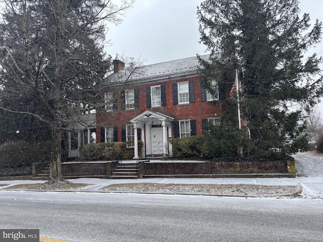 view of front of home featuring brick siding and a chimney