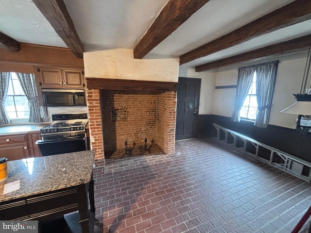 kitchen featuring a wealth of natural light, gas stove, brick floor, and black microwave